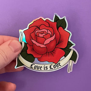 A holographic sticker of a red rose drawn in the traditional American tattoo style with a tattoo banner that says &quot;Love Is Love&quot; in a gothic font. The red rose has pink petals as accents.
